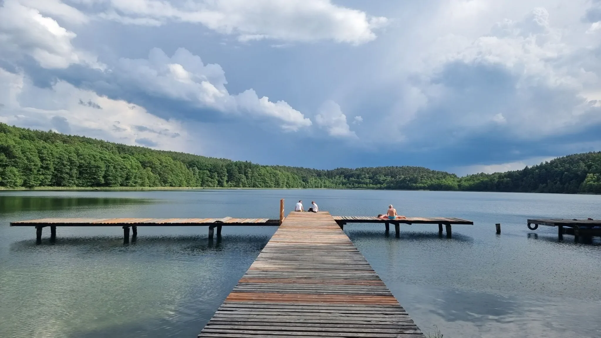 Widok z lotu ptaka na spokojne jezioro otoczone lasem i domkami letniskowymi