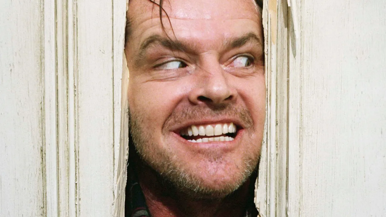 Jack Nicholson as Jack Torrance, asiendo un agujero en una puerta, perfecto para películas de terror psicológico sin jumpscares ni sustos fáciles.